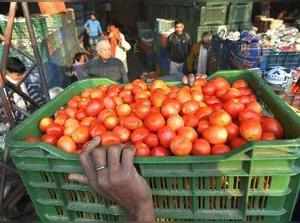 New Delhi: A porter carries a basket of tomatoes at the wholesale market at Azad...