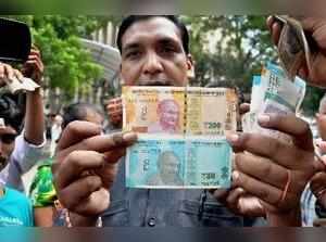 New Delhi: A man shows new currency notes of Rs 200 and Rs 50 outside the Reserv...