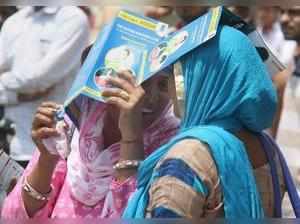 Gurugram: Women take shade on a hot afternoon in Gurugram on Sunday. PTI Photo...