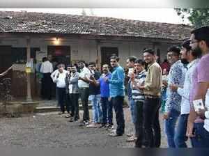 RPT:Surat: Voters showing their voter ID cards at a polling booth during Gujarat...