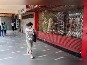 New Delhi: A woman walks past a closed shop during a strike by traders and worke...