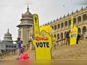 Bengaluru: Workers put promotional posters for the forthcoming Karnataka Assembl...