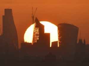 Sun is seen rising over skyscrapers in the City of London financial district in London