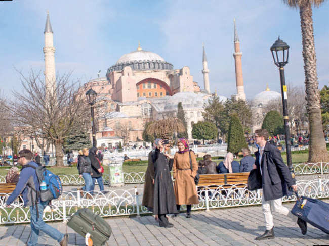 Tourists walk past the Hagia Sofia in the famous Sultanahmet District in Istanbul, Turkey