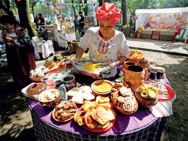 A woman dressed in national Belarussian clothes prepares food as she takes part in the ‘Beraginya’ festival of folklore art in the town of Oktyabrski