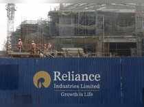 FILE PHOTO: Labourers work behind an advertisement of Reliance Industries Limited at a construction site in Mumbai
