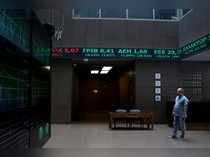 A man stands under a stock ticker showing stock options inside the Athens stock exchange building in Athens