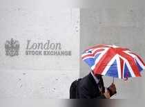 A worker shelters from the rain as he passes the London Stock Exchange in London