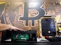 A cryptocurrency mining computer is seen in front of bitcoin logo during the annual Computex computer exhibition in Taipei