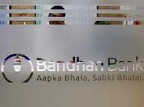 FILE PHOTO - An employee of Bandhan Bank is seen behind a glass bearing the bank's logo inside a branch office in Kolkata