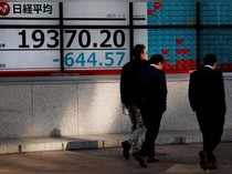 Men walk past an electronic board showing Nikkei average outside a brokerage in Tokyo