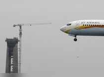 A Jet Airways passenger plane prepares to land past a new air traffic control tower under construction in New Delhi