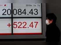 FILE PHOTO: A man looks at an electronic board showing the Nikkei stock index outside a brokerage in Tokyo