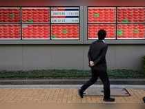 A man looks at an electronic board showing the Nikkei stock index outside a brokerage in Tokyo
