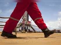 An oil worker walks past a drilling rig at an oil well operated by Venezuela's state oil company PDVSA in Morichal
