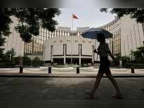 FILE PHOTO: Woman walks past the headquarters of the PBOC in Beijing