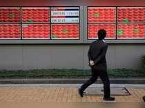 FILE PHOTO: A man looks at an electronic board showing the Nikkei stock index outside a brokerage in Tokyo