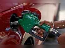 A worker holds a nozzle to pump petrol into a vehicle at a fuel station in Mumbai