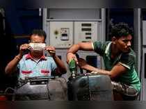 FILE PHOTO: A worker checks a 500 Indian rupee note as a man fills diesel in containers at a fuel station in Kolkata
