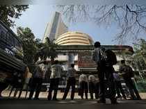 People look at a screen displaying the Sensex results on the facade of the Bombay Stock Exchange (BSE) building in Mumbai