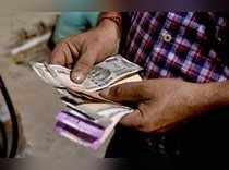 Kolkata: A customer counts Indian Rupee notes at a fuel station, in Kolkata on T...