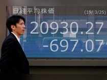 A man walks past an electronic board showing the Nikkei stock index outside a brokerage in Tokyo