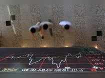 People walk under an electronic board showing stock information at the Shanghai Stock Exchange in Lujiazui Financial Area in Shanghai