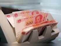 Chinese 100 yuan banknotes in a counting machine while a clerk counts them at a branch of a commercial bank in Beijing