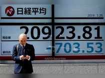 A man stands in front of an electronic board showing the Nikkei stock index outside a brokerage in Tokyo
