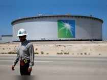 FILE PHOTO: An Aramco employee walks near an oil tank at Saudi Aramco's Ras Tanura oil refinery and oil terminal