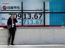 A man stands in front of an electronic board showing the Nikkei stock index outside a brokerage in Tokyo