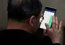 An investor checks stock information on a mobile phone at a brokerage house in Shanghai,