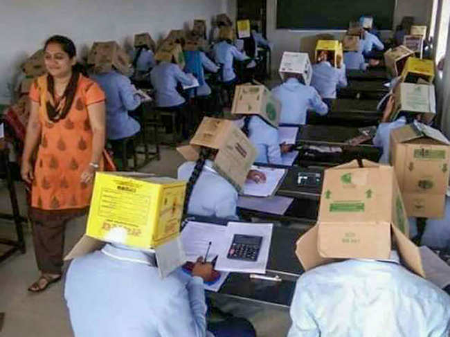 First-year science students of Bhagat PU College sit for a midterm exam with cardboard cartons covering their heads — with a hole cut out in the front for their face, in Haveri district of Karnataka.