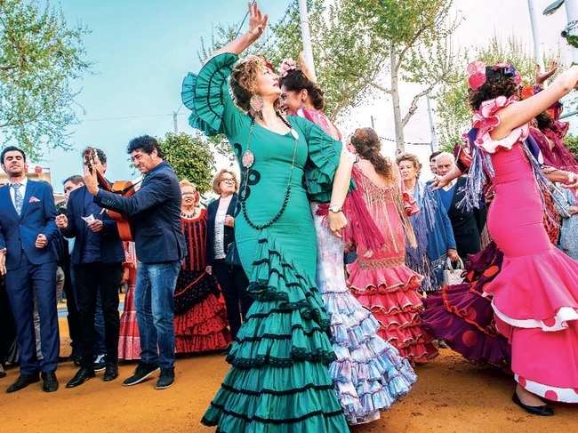 Women wear traditional Sevillana dresses showcase the traditional dance moves of the region as they partake in the Feria de Abril, an annual event that takes place annually during April in Seville, Spain.