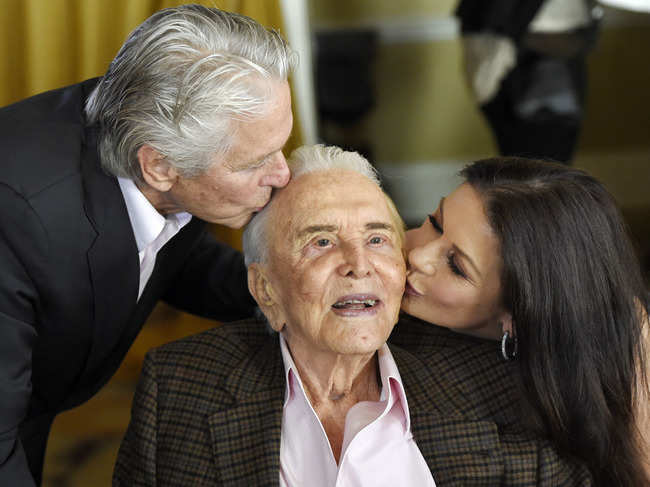 Kirk Douglas (C) ​gets kisses from son Michael Douglas (L) and daughter-in-law Catherine Zeta-Jones (R) during his 100th birthday party in ​2016 ​.