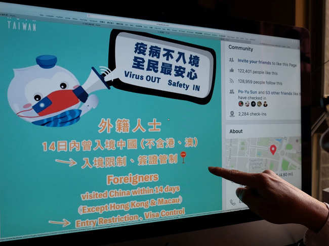 This photo illustration taken on February 14, 2020 shows a man pointing to a webpage from Taiwan's Ministry of Foreign Affairs’ Facebook account, used to promote the prevention of the deadly COVID-19 coronavirus, in Taipei.