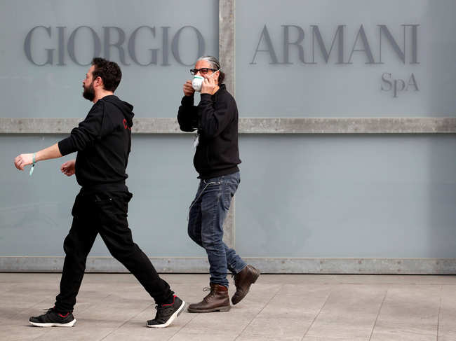 Workers walk past the Giorgio Armani logo outside the theatre where the Italian designer said his Milan Fashion Week show would take place to safeguard the health of press and buyers after a coronavirus outbreak in northern Italy.