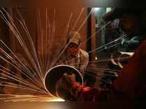 A worker cuts metal inside a workshop manufacturing metal pipes in Mumbai