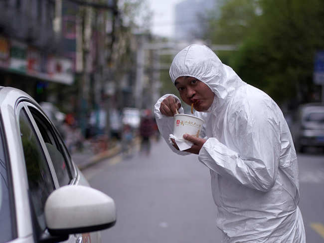 ​A man wearing a protective suit eats his breakfast, Wuhan signature dish of hot dried noodles, Regan Noodle, on a street in Wuhan, the epicenter of China's coronavirus disease (COVID-19) outbreak.