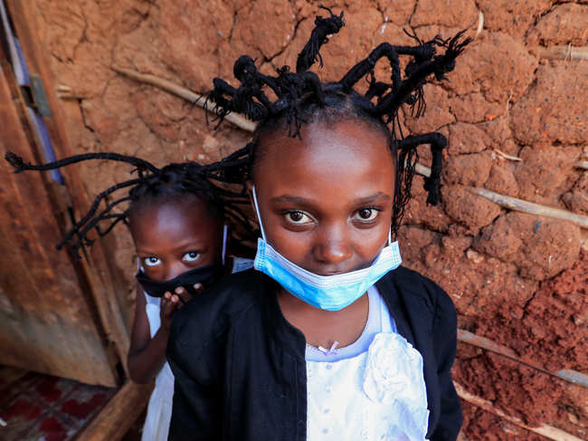 Martha Apisa, 12, and Stacy Ayuma, 8, pose for a photograph outside their house after plaiting with the 'coronavirus' hairstyle, designed to emulate the prickly appearance of the virus under a microscope, as a fashion statement against the spread of the coronavirus disease (COVID-19), at Mama Brayo Beauty Salon within Kambi-Muru village of Kibera slums in Nairobi, Kenya