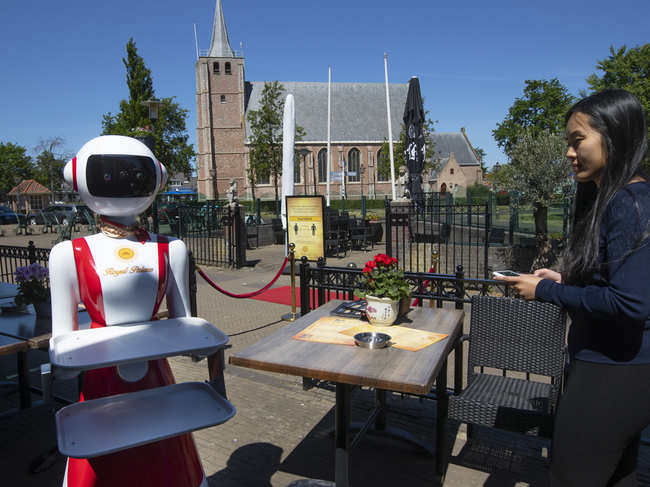 Leah Hu uses a tablet to demonstrate the use of a robot for serving purposes or for dirty dishes collection, as part of a tryout of measures to respect social distancing and help curb the spread of the COVID-19 coronavirus, at the family's Royal Palace restaurant in Renesse, south-western Netherlands.