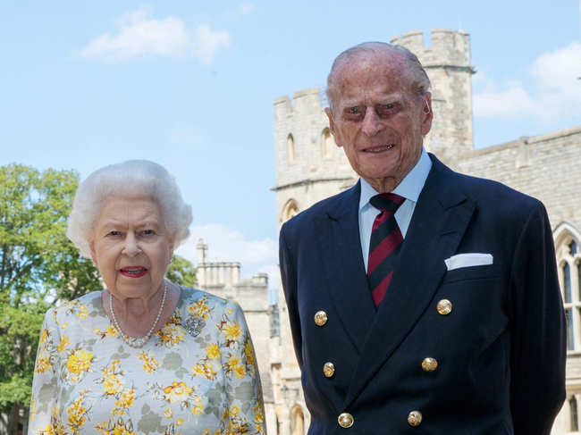 In this handout photo issued by the Press Association, Queen Elizabeth II and the Duke of Edinburgh pose in the quadrangle of Windsor Castle ahead of his 99th birthday on June 1, 2020 in Windsor, United Kingdom. The Queen is wearing an Angela Kelly dress with the Cullinan V diamond brooch. The Duke is wearing a Household Division tie.