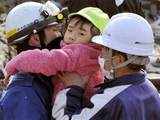 Rescue workers hold a girl they rescued from a building