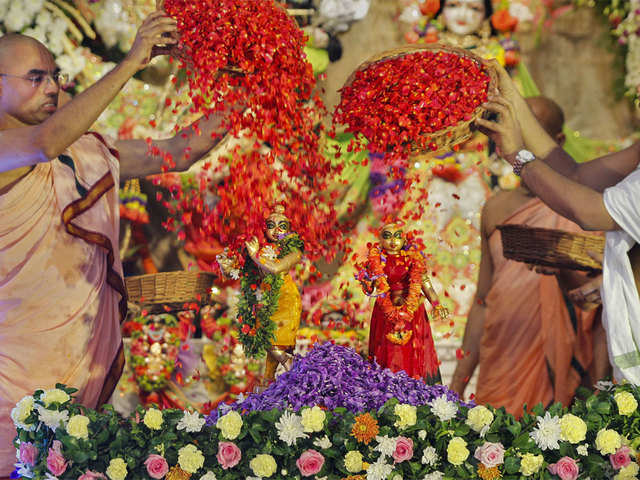 Priests shower flower petals on idols of Lord Krishna and Radha during Janmashtami celebrations