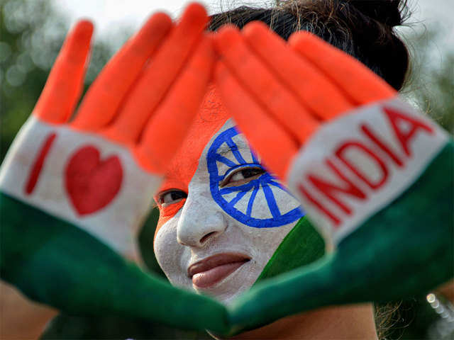 A girl with her face and hands painted in tricolour poses for a photograph.