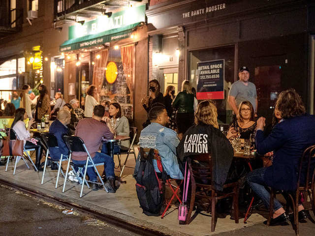 People dine outdoors, on the sidewalk in the West Village in New York City.