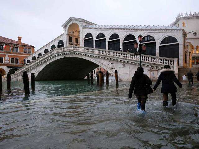 ​People walk past the Rialto Bridge