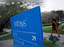 An employee walks past a signage board in the Infosys campus at the Electronics City IT district in Bangalore