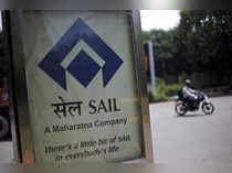 A motorcyclist rides past an advertisement of SAIL at a street in New Delhi