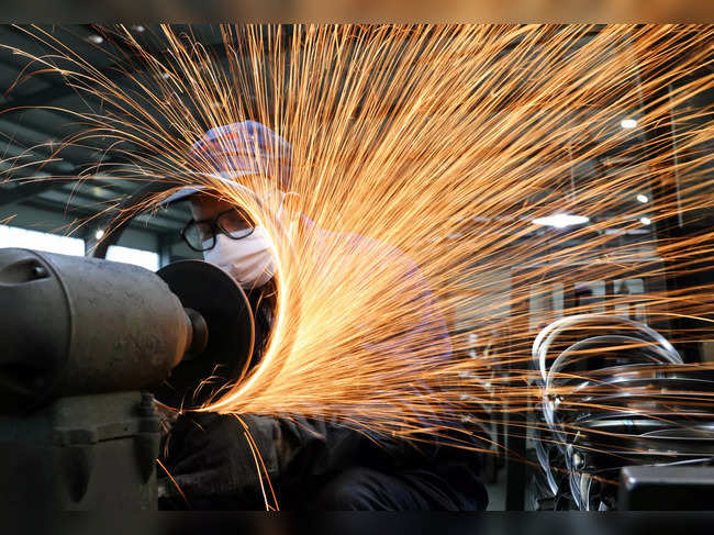 Worker wearing a face mask works on a production line manufacturing bicycle steel rim at a factory in Hangzhou, Zhejiang